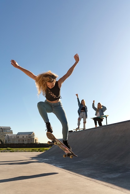 Ragazza del colpo pieno che salta con lo skateboard