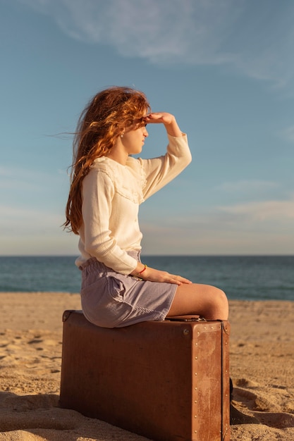 Ragazza del colpo pieno che si siede sulla valigia