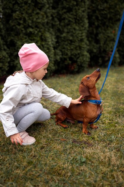 Ragazza del colpo pieno con il cane sveglio all'aperto