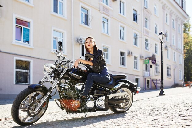 Ragazza del motociclista in una giacca di pelle su una moto