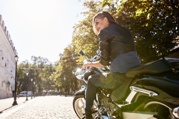 Ragazza del motociclista in una giacca di pelle su una moto