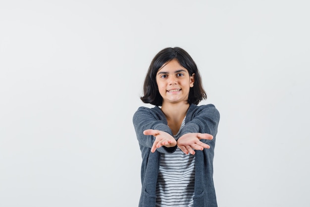 Ragazza del preteen in camicia, giacca alzando la mano mentre posa come mostrare qualcosa e sembra felice,