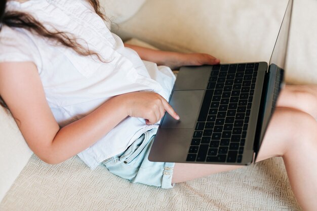 Ragazza del primo piano che gioca sul computer portatile