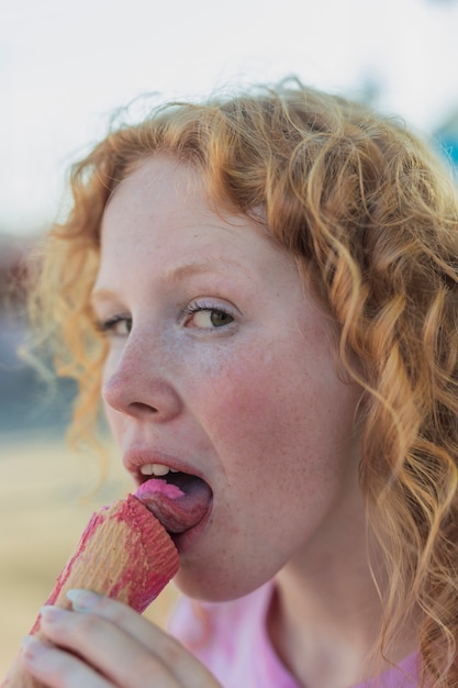 Ragazza del primo piano che mangia il gelato rosa