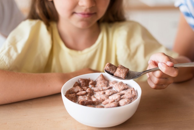 Ragazza del primo piano che mangia latte e cereali