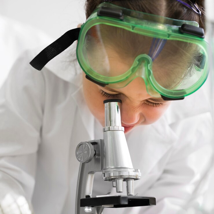 Foto gratuito ragazza del primo piano che osserva tramite il microscopio