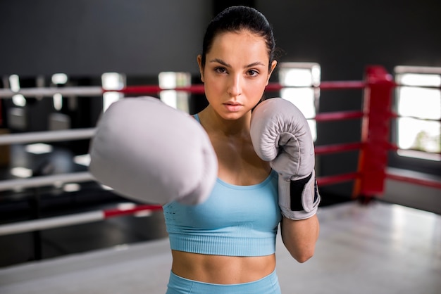 Ragazza del pugile che posa in palestra