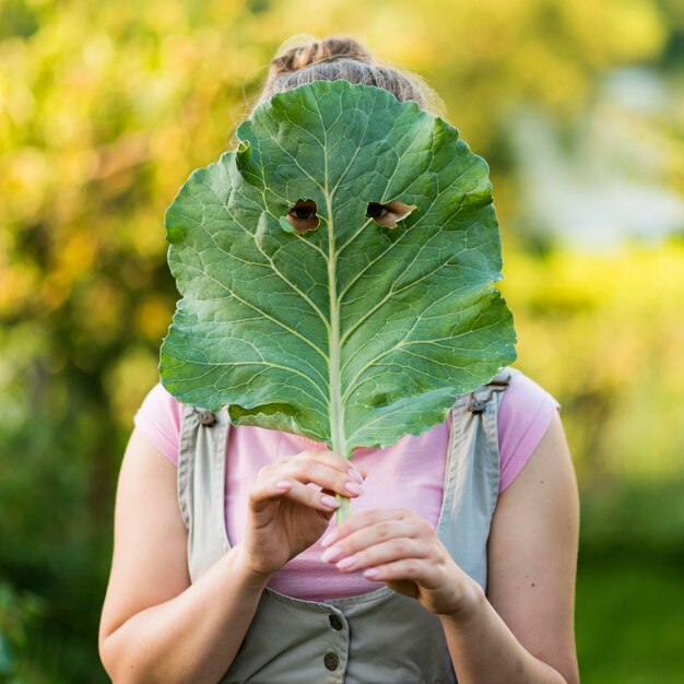 Ragazza del tiro medio che copre il viso con foglia