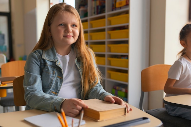 Ragazza del tiro medio che impara a scuola