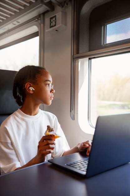 Ragazza del tiro medio con il computer portatile in treno