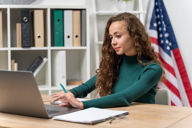 Ragazza del tiro medio con le cuffie e il computer portatile all'interno