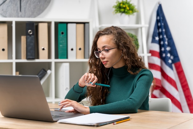 Ragazza del tiro medio con lo studio delle cuffie e del computer portatile