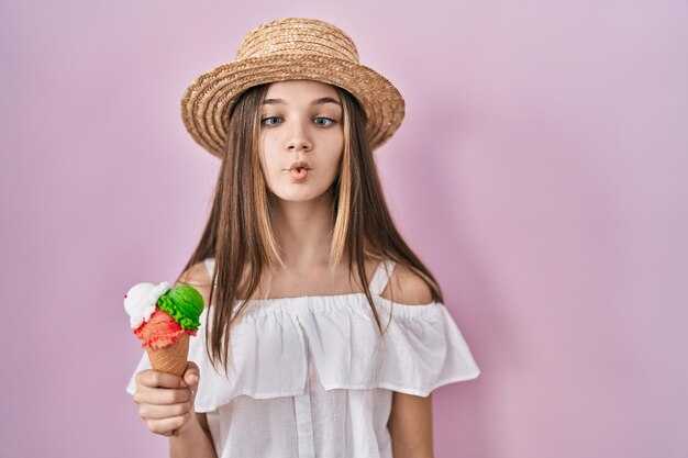 Ragazza dell'adolescente che tiene il gelato che fa la faccia di pesce con le labbra espressione divertente gesto pazzo e comico