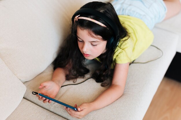 Ragazza dell'angolo alto che si siede sullo strato con il telefono