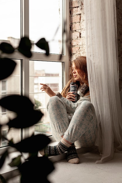 Ragazza della foto a figura intera che guarda fuori dalla finestra