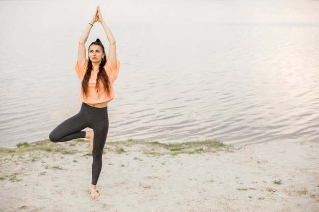 Ragazza della foto a figura intera che si esercita vicino al lago