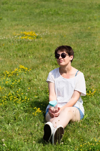 Ragazza della foto a figura intera che si siede sull'erba