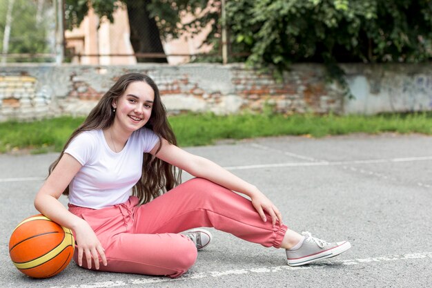 Ragazza della possibilità remota che tiene una pallacanestro all'aperto