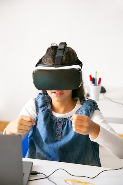 Ragazza della scuola che gioca e utilizza l'auricolare VR