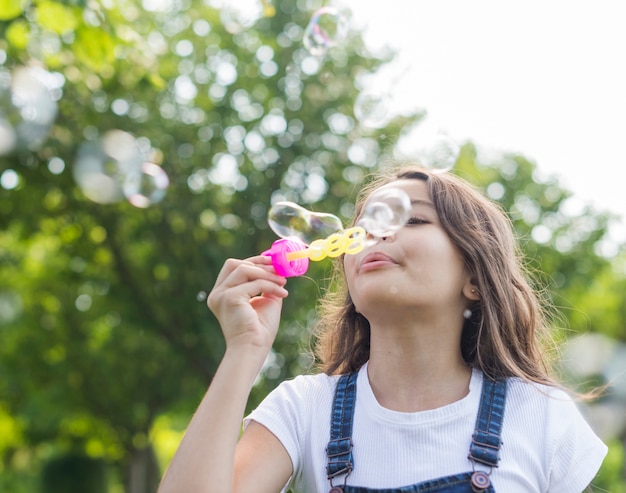 Ragazza di angolo basso che fa le bolle di sapone