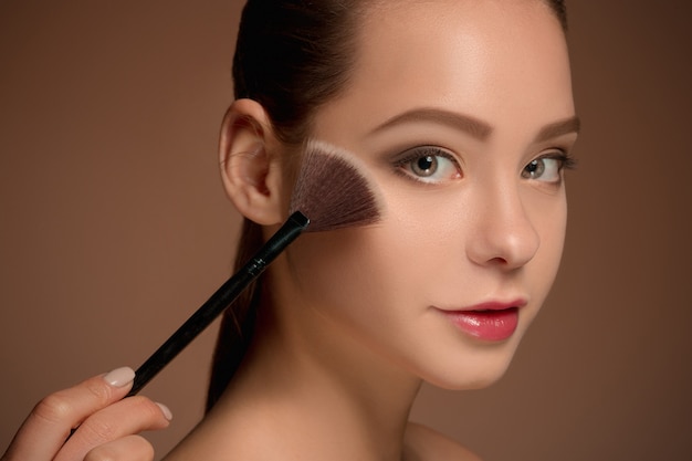 Ragazza di bellezza con pennello trucco. Pelle perfetta Applicare il trucco