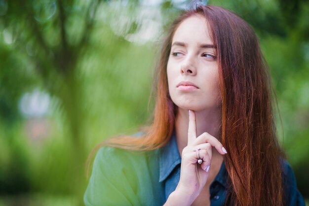 Ragazza di colore rosso che tocca il mento all&#39;aperto