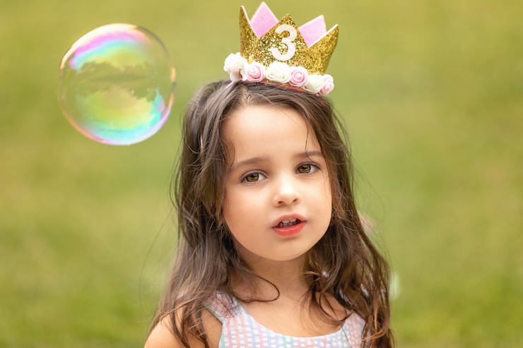 Ragazza di compleanno che gioca con le bolle di sapone all'aperto