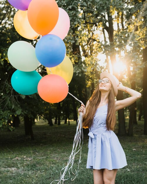 Ragazza di compleanno di angolo basso con gli aerostati al sole