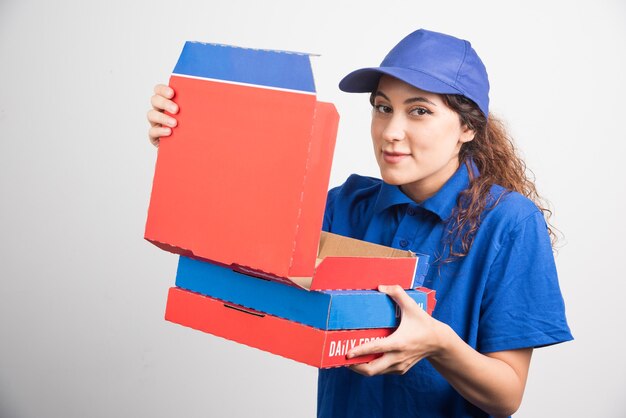 Ragazza di consegna pizza aprendo una delle scatole di pizza su priorità bassa bianca