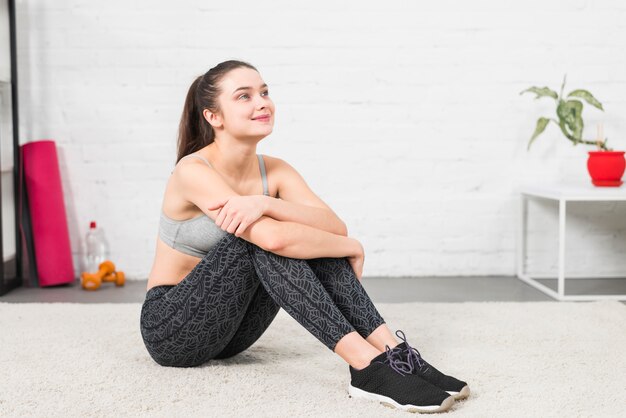 Ragazza di forma fisica che si siede sul pavimento