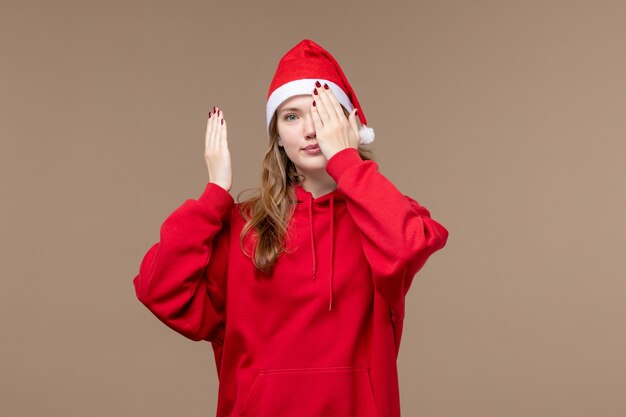 Ragazza di natale di vista frontale che copre il suo fronte sul natale di festa del modello del fondo marrone