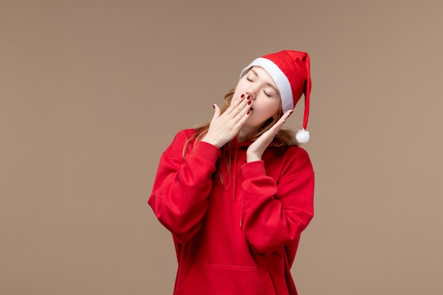 Ragazza di natale di vista frontale che prova a dormire sulle emozioni di natale di festa del fondo marrone