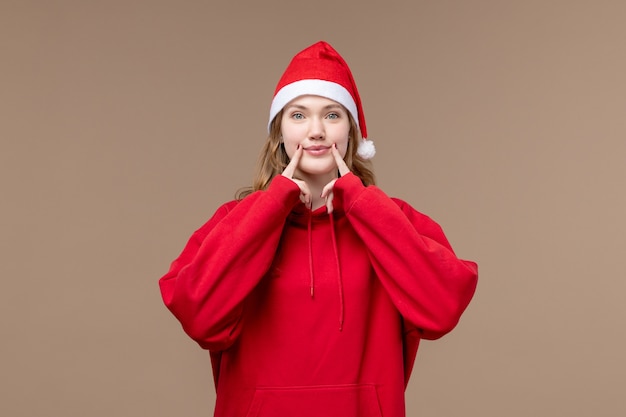 Ragazza di natale di vista frontale che prova a sorridere sul natale di festa del modello del fondo marrone