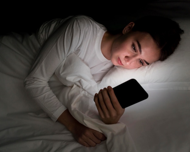 Ragazza di notte a letto con il telefono