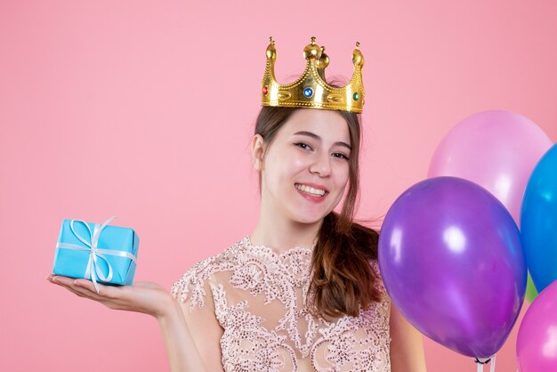 Ragazza di partito felice vista frontale del primo piano con corona che tiene presente e palloncini