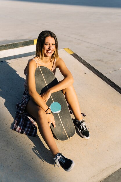 Ragazza di pattinatore seduta e sorridente