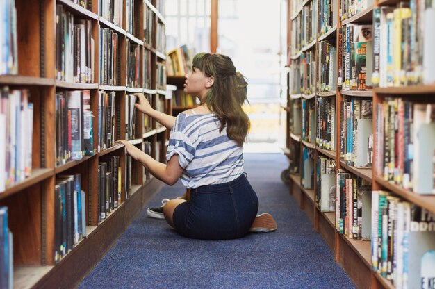 Ragazza di seduta in cerca di libro