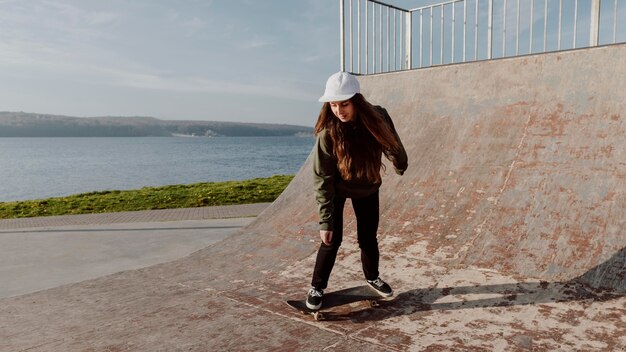 Ragazza di skateboarder sulla rampa campo lungo