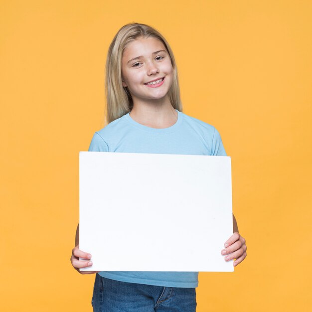 Ragazza di smiley che tiene foglio di carta bianco