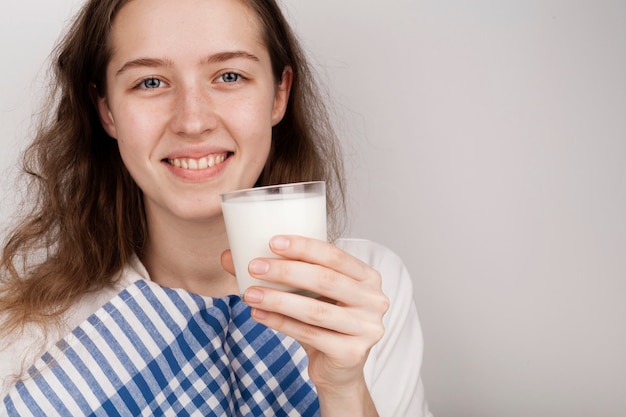 Ragazza di smiley che tiene un bicchiere di latte con lo spazio della copia