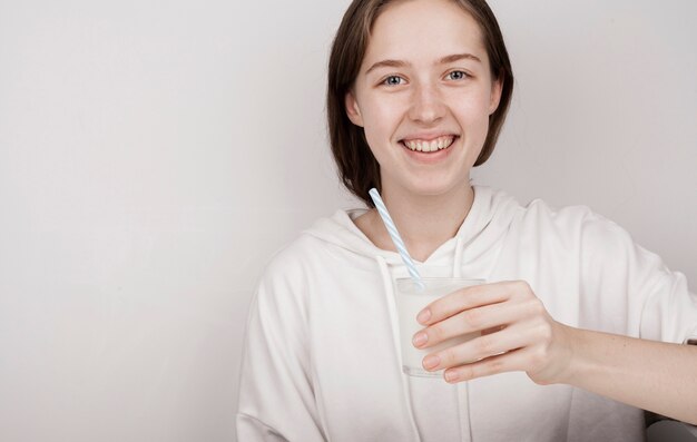 Ragazza di smiley che tiene un bicchiere di latte con lo spazio della copia