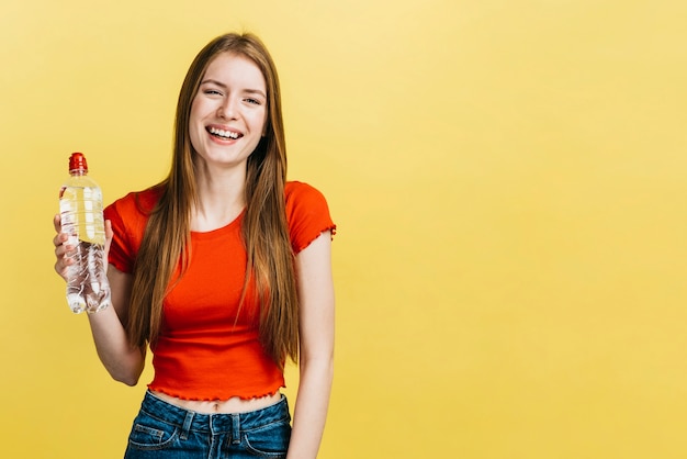 Ragazza di smiley che tiene una bottiglia con lo spazio della copia