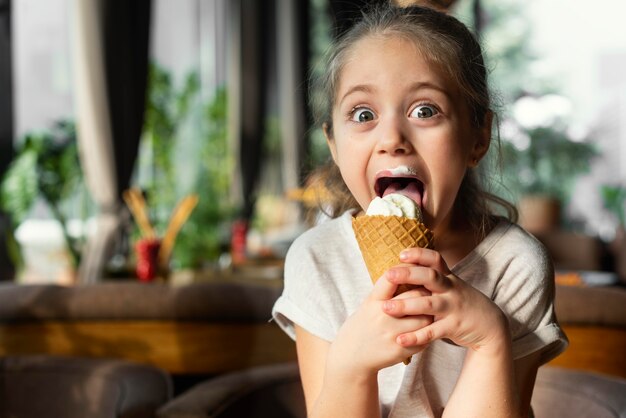 Ragazza di smiley del colpo medio che mangia il gelato