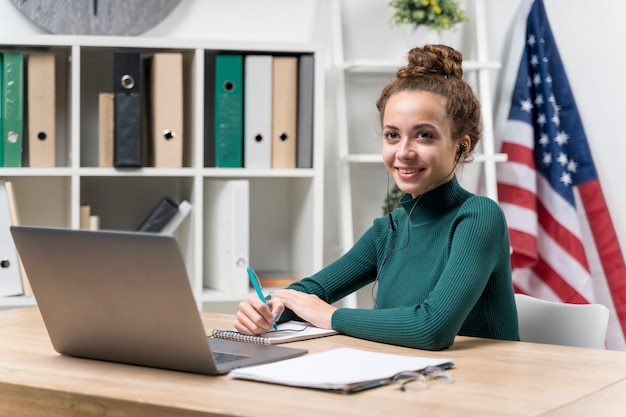 Ragazza di smiley di tiro medio con cuffie e laptop