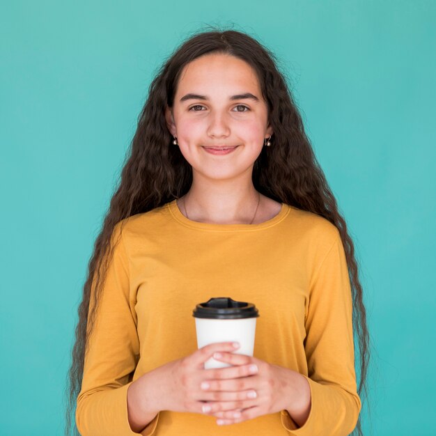 Ragazza di smiley di vista frontale che tiene la sua bevanda