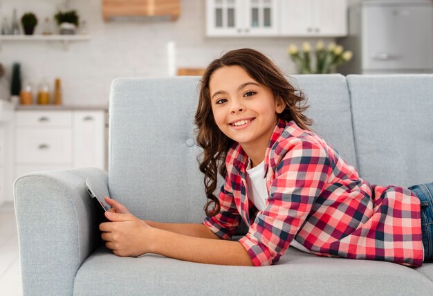 Ragazza di smiley di vista laterale con la compressa a casa