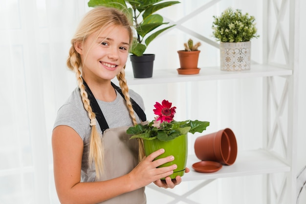 Ragazza di smiley di vista laterale con vaso di fiori