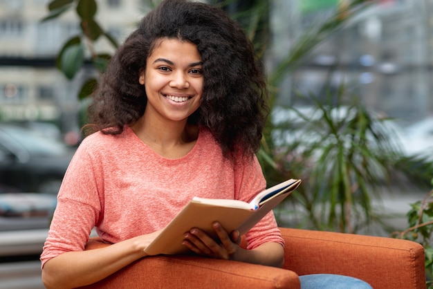 Ragazza di smiley sulla lettura della poltrona