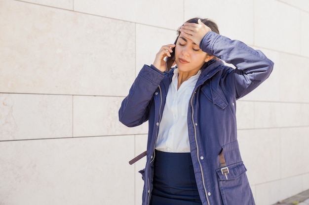 Ragazza di ufficio stanca che parla sul telefono cellulare