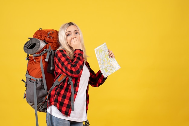 Ragazza di viaggiatore perplesso vista frontale con il suo zaino che tiene mappa